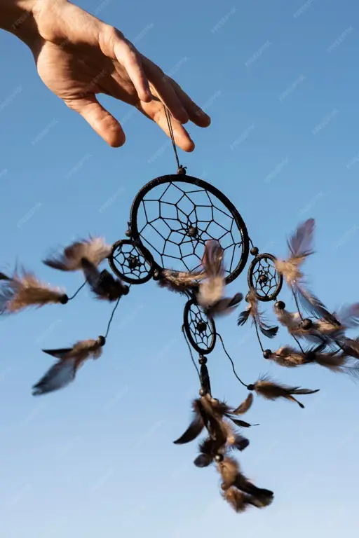 Dua tangan memegang sebuah dreamcatcher.