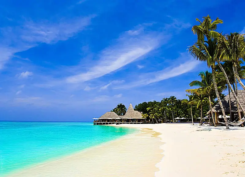 Pemandangan pantai yang indah dengan air laut biru, pasir putih, dan langit cerah