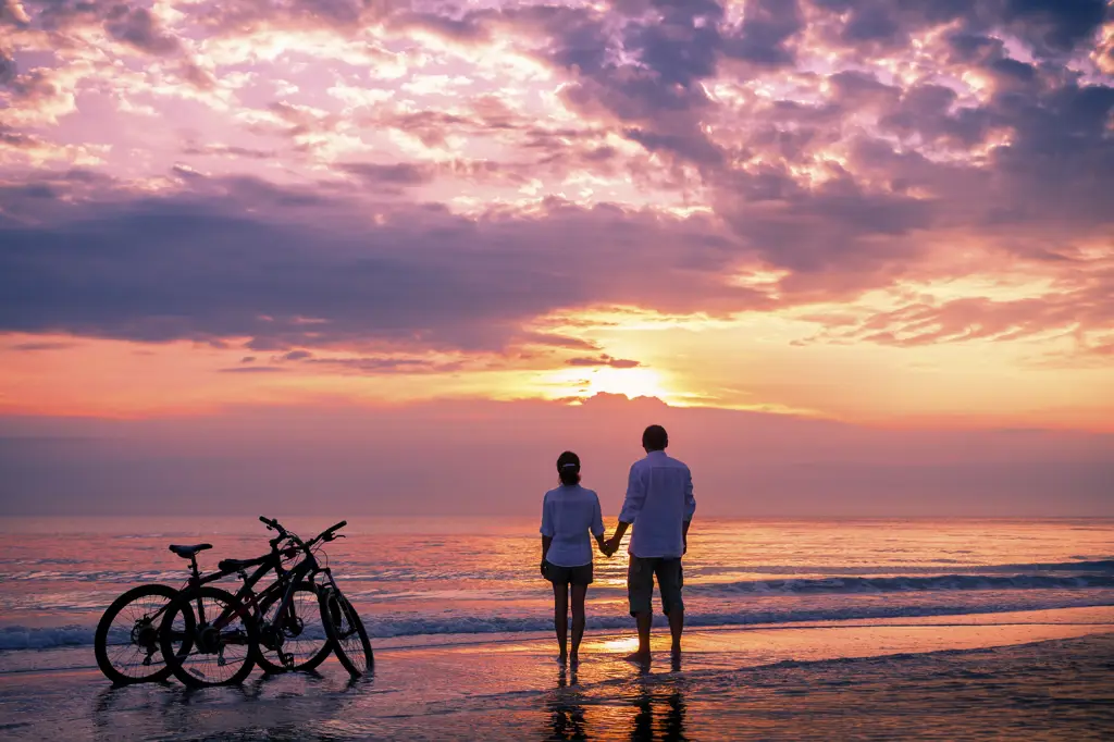 Pasangan berjalan di pantai saat matahari terbenam