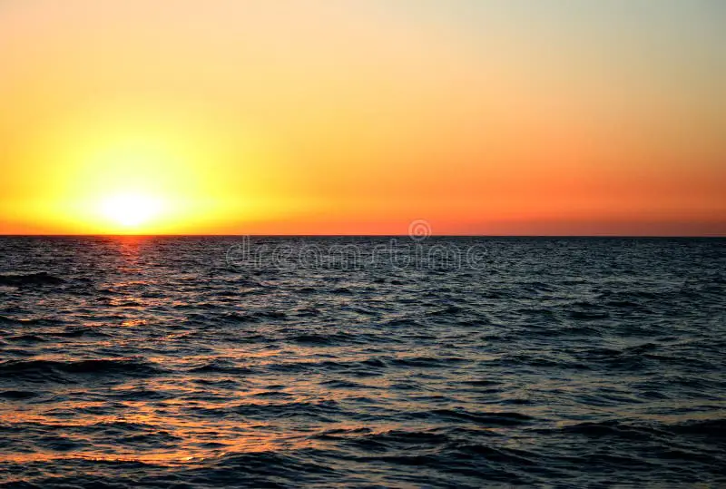 Foto matahari terbenam di atas laut yang melambangkan kerinduan